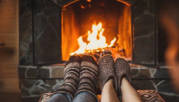 A couple warming their feet around a fireplace
