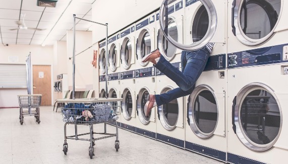 A women inside a washing machine at a laundromat