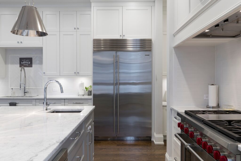 Stainless steel refrigerator beside white kitchen cabinet