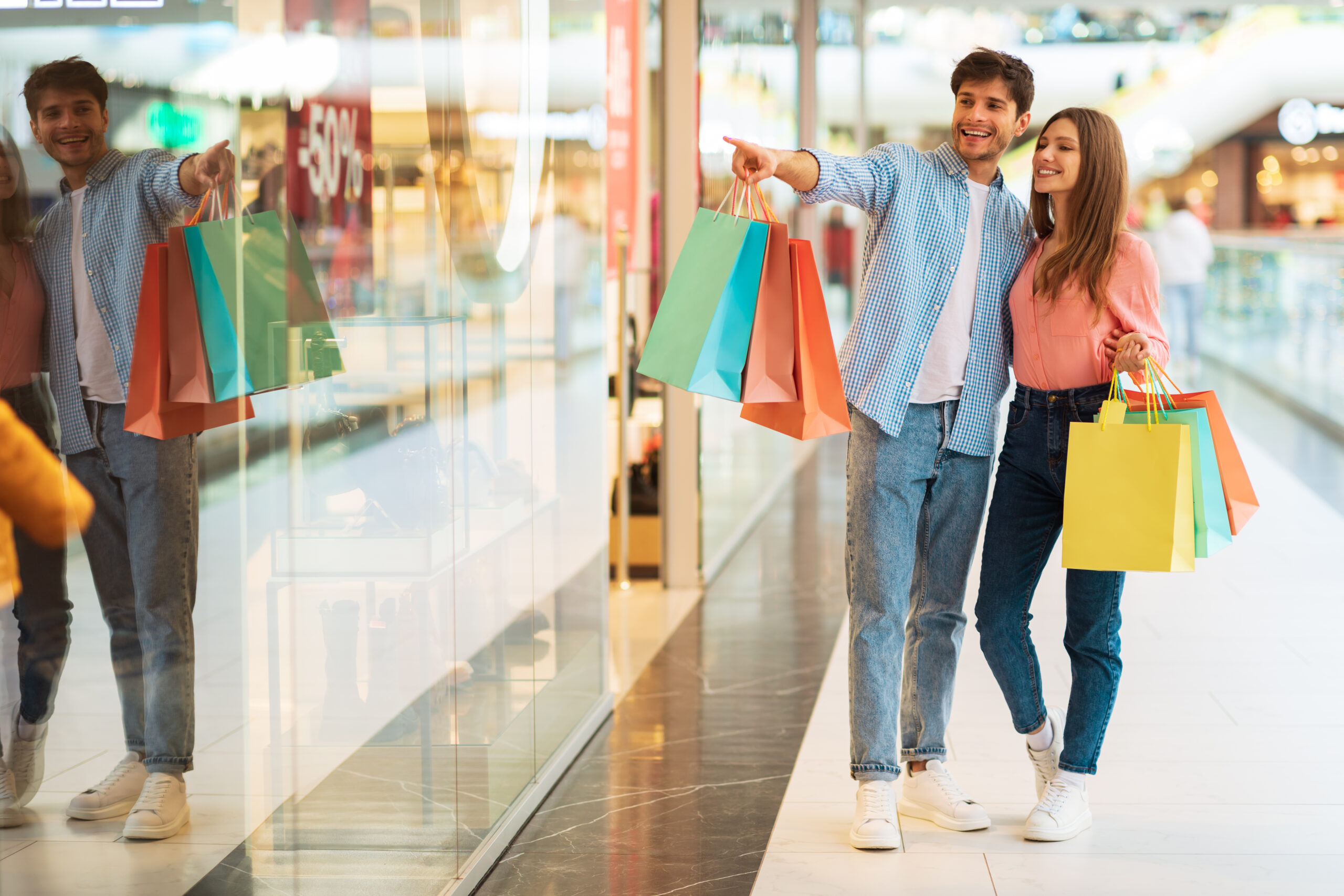 Couple doing shopping pointing finger shop window mall 1 scaled