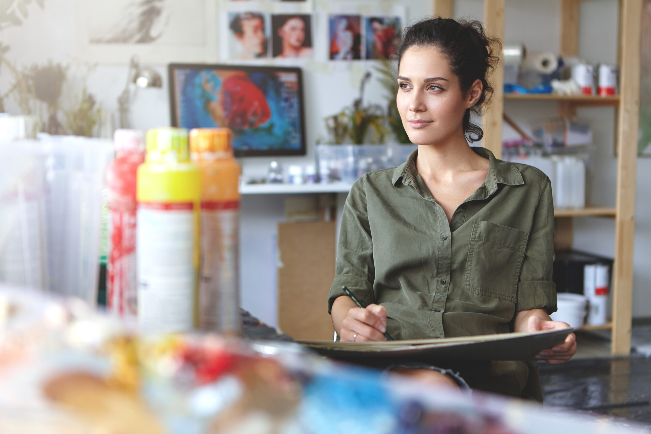 Portrait young female creative occupation sitting modern workshop working enjoying process creating something beautiful looking sideways with pleased inspired expression her face scaled