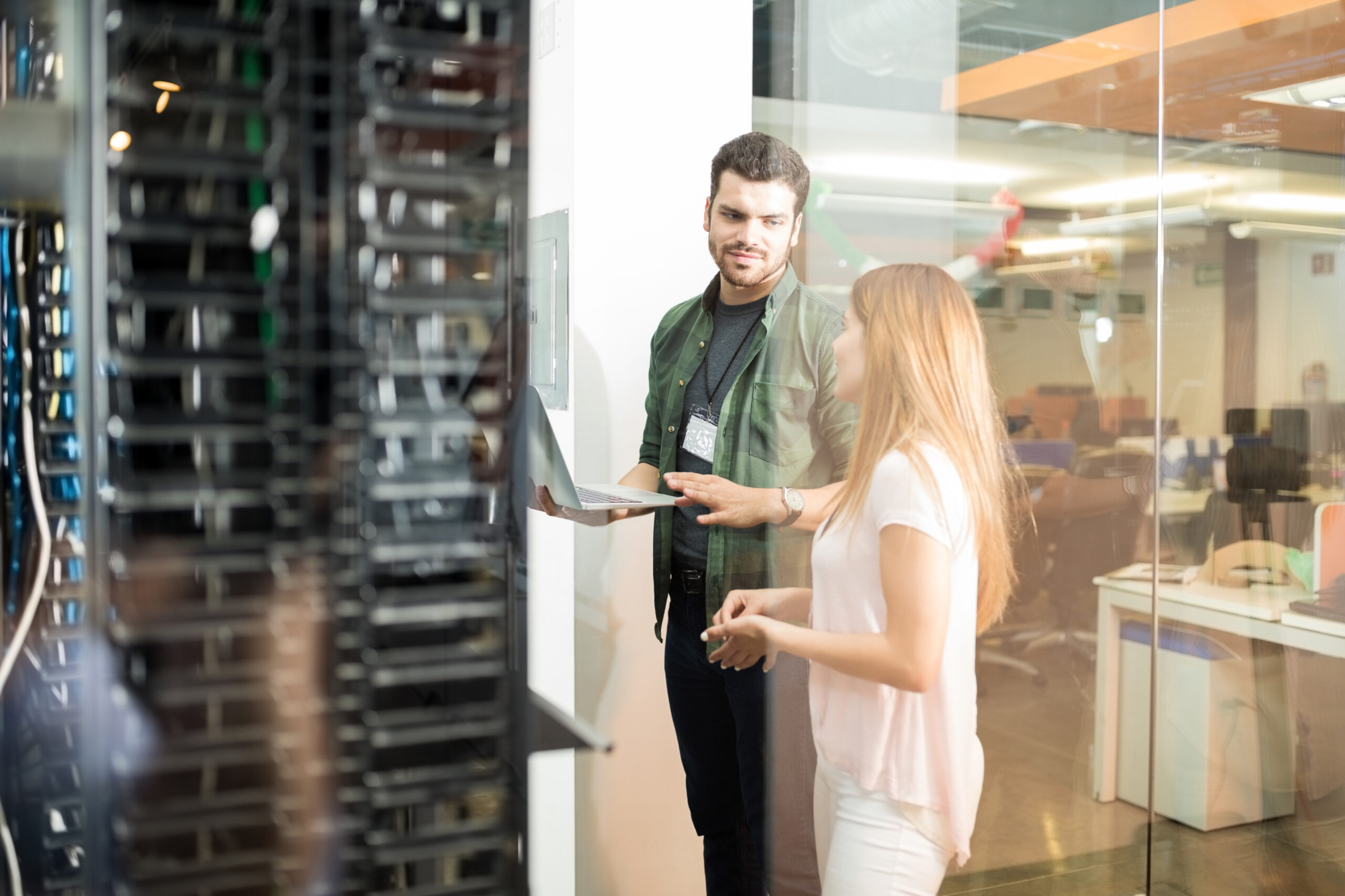 Two business people standing server room with laptop discussing scaled