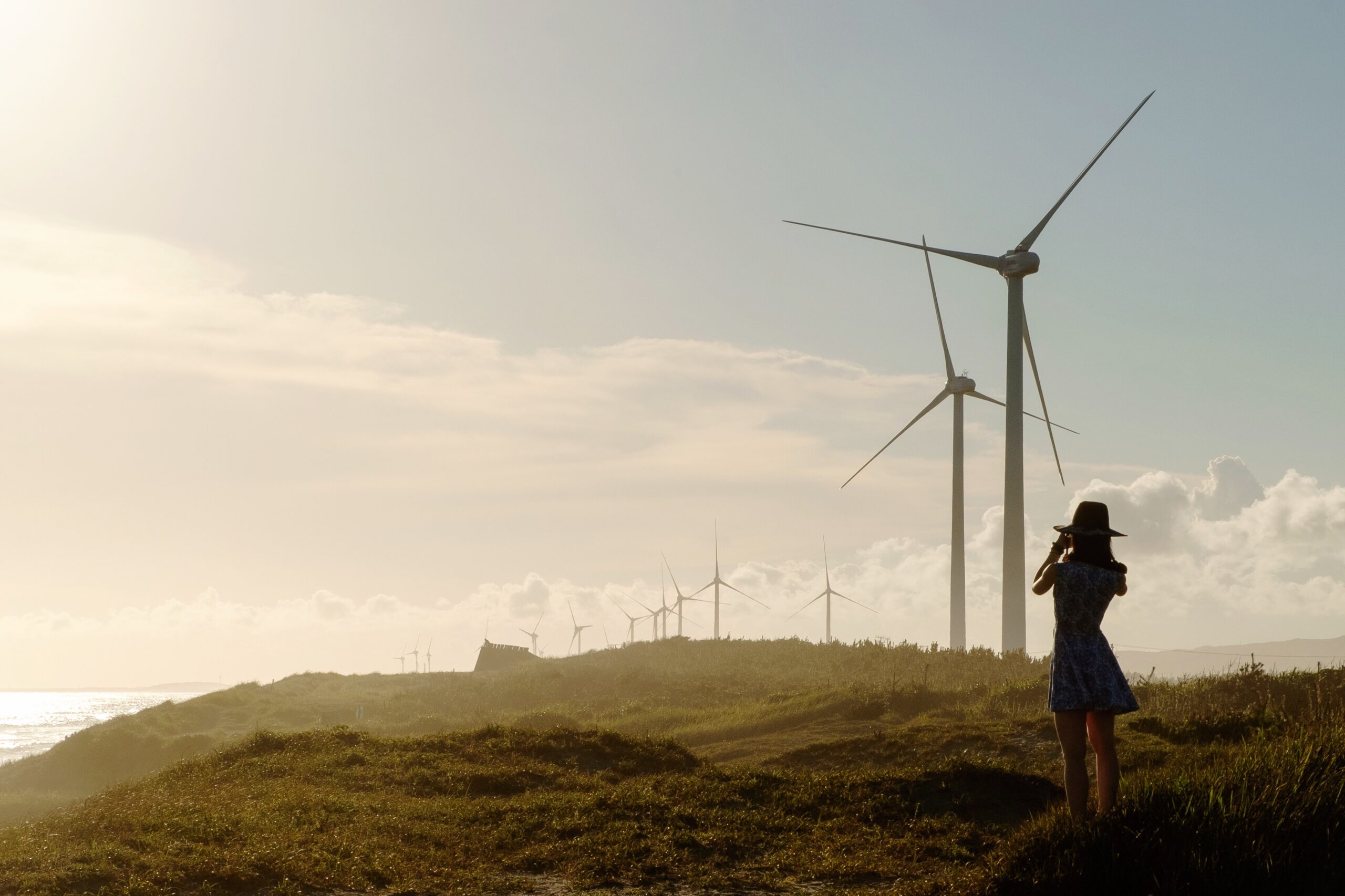 Woman standing field with wind turbines against sky scaled
