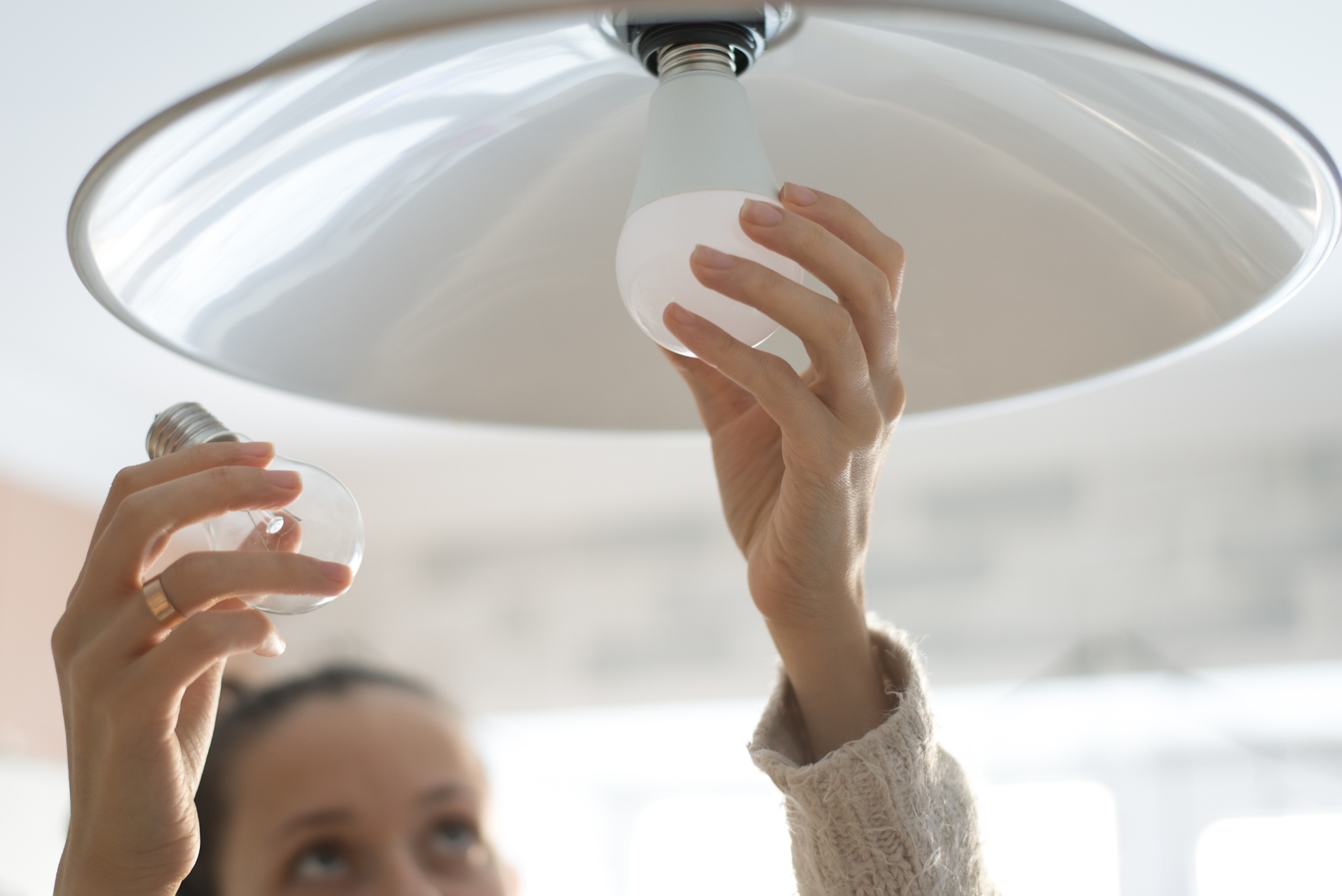 A woman replaces an incandescent light bulb for an energy-efficient led bulb