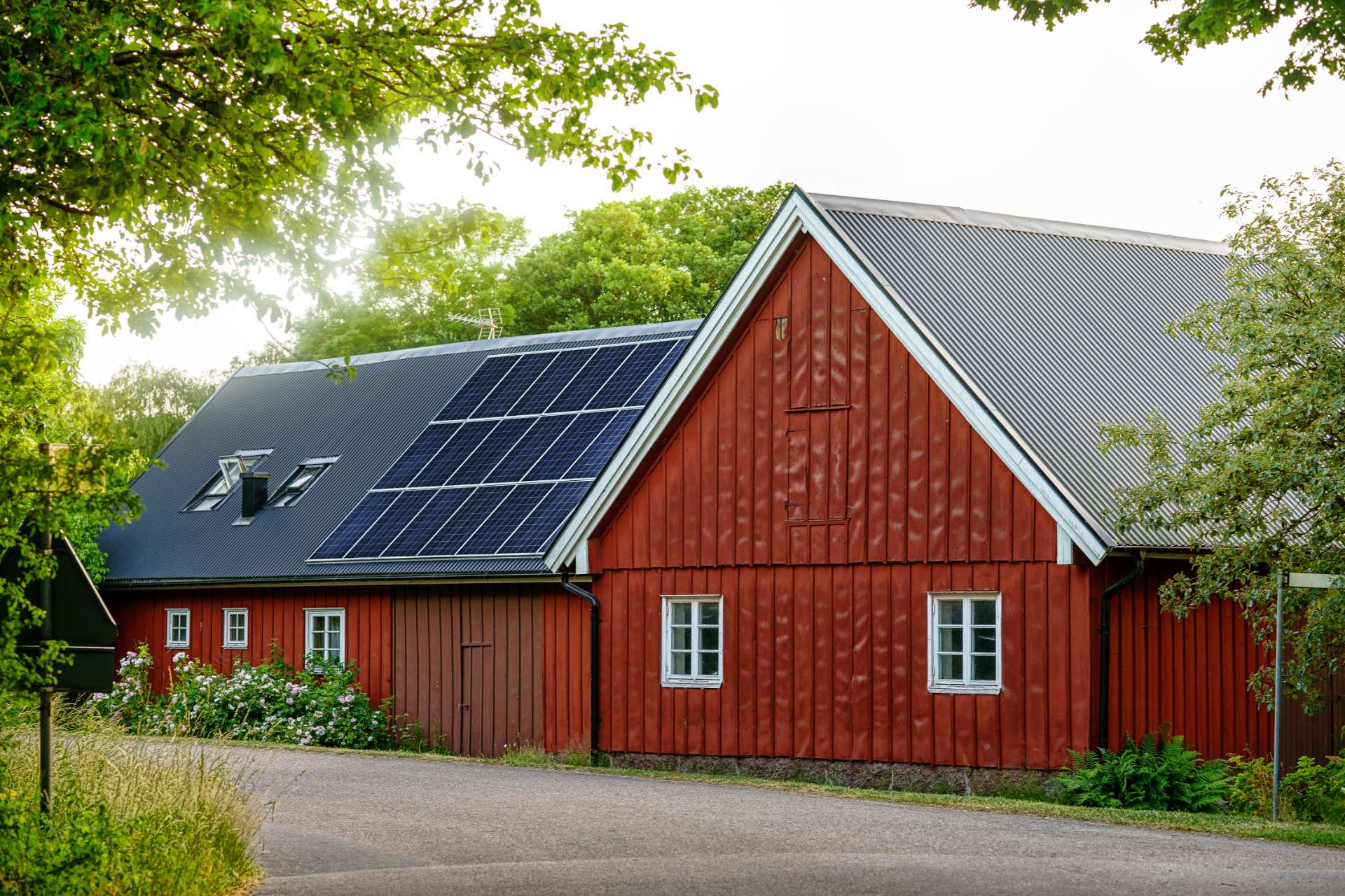 Rooftop solar panels on a red house in a wooded area