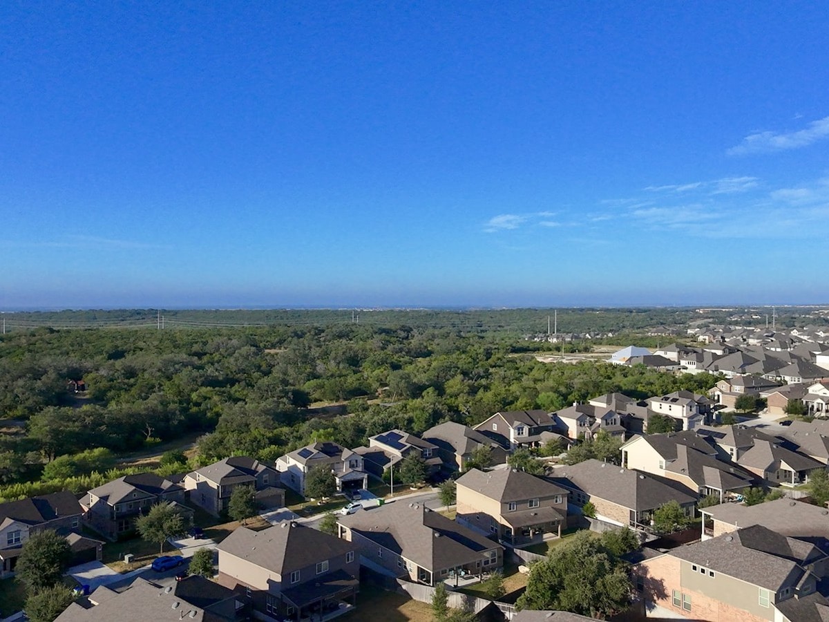 Why Are Electricity Bills Going Up On The Ercot And Pjm Grids? 2 Aerial view of a texas suburban neighborhood under a bright blue sky