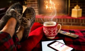 Someone with a steaming cup of hot chocolate getting warm by the fireplace