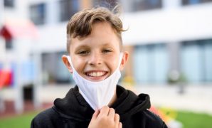 A young student wears a mask at school