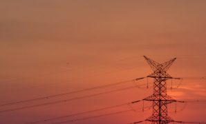 Electricity transmission pylon silhouetted against a Texas sunset representing rising grid demand